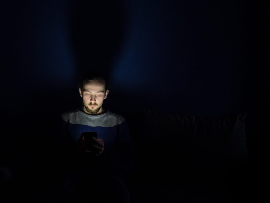 man looking at phone in a dark room